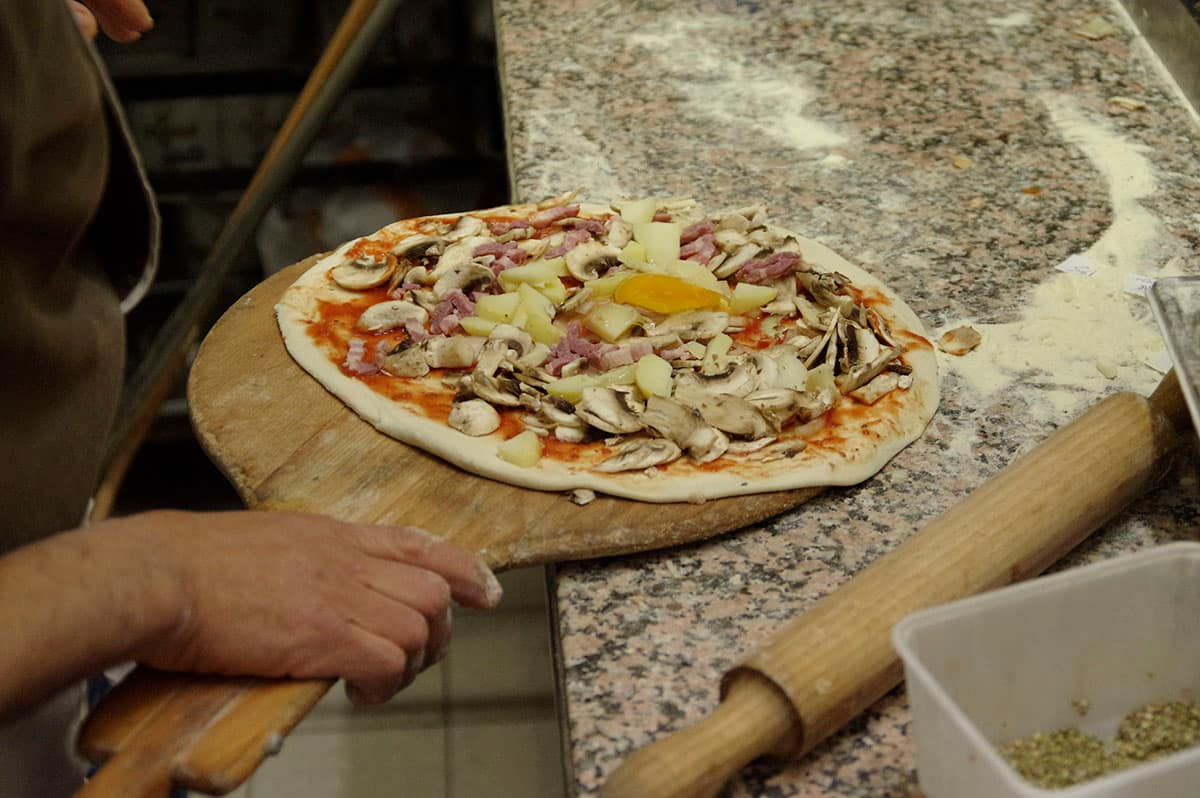 Pizza garnie sur la pelle en bois, juste avant l’enfournement.